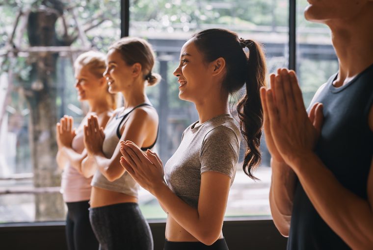 Group of young people practicing yoga In the prayer position at gym, Concept of relaxation and meditation