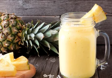 a photo of a smoothie with a pineapple in the background
