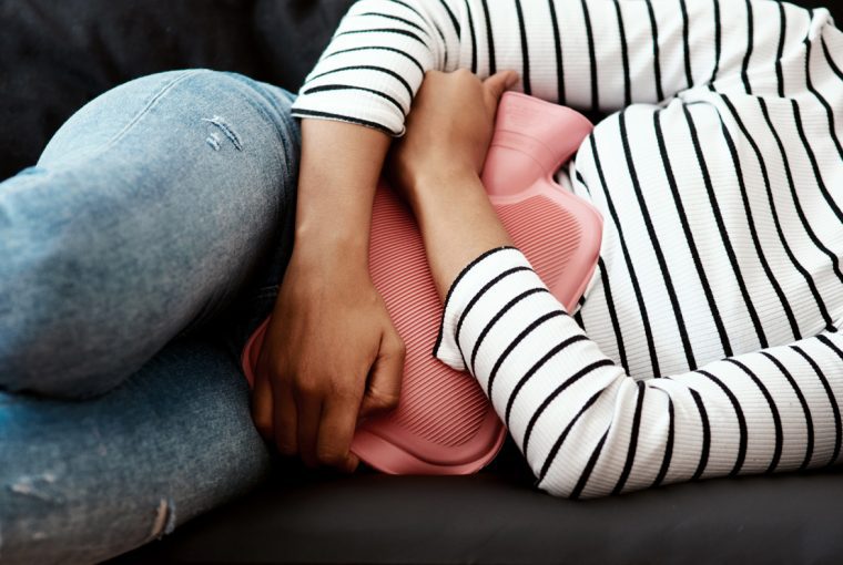 a woman using a heating pad to help with period cramps