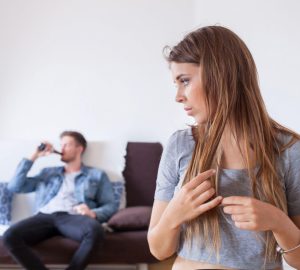 a woman looking back at a man drinking a beer