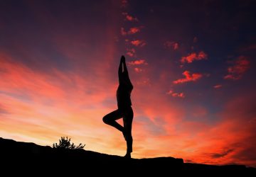 a woman doing yoga with a sunset background
