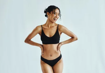 a woman standing in black underwear smiling