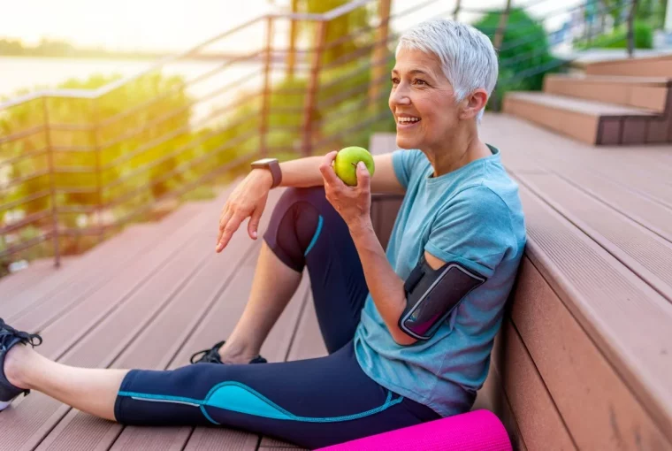 a woman sitting outside eating an apple