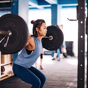 a woman doing squats in a squat rack
