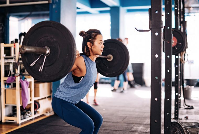 a woman doing squats in a squat rack