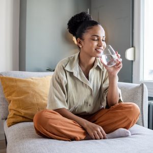 a woman drinking water on her bed