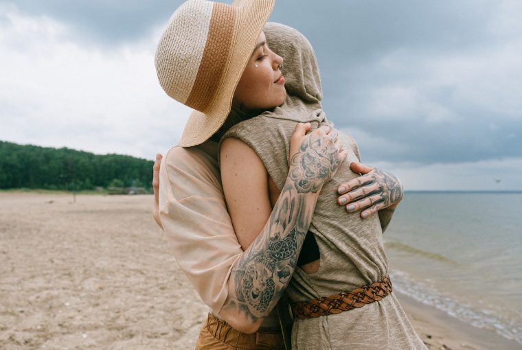 2 woman embracing each other at the beach