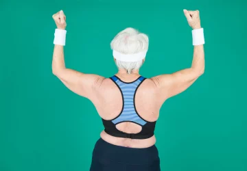 a senior woman flexing her muscles against a green backdrop