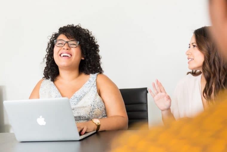 a group of young smiling adults with a computer