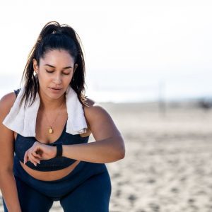 a woman exercising outdoors and looking at her watch
