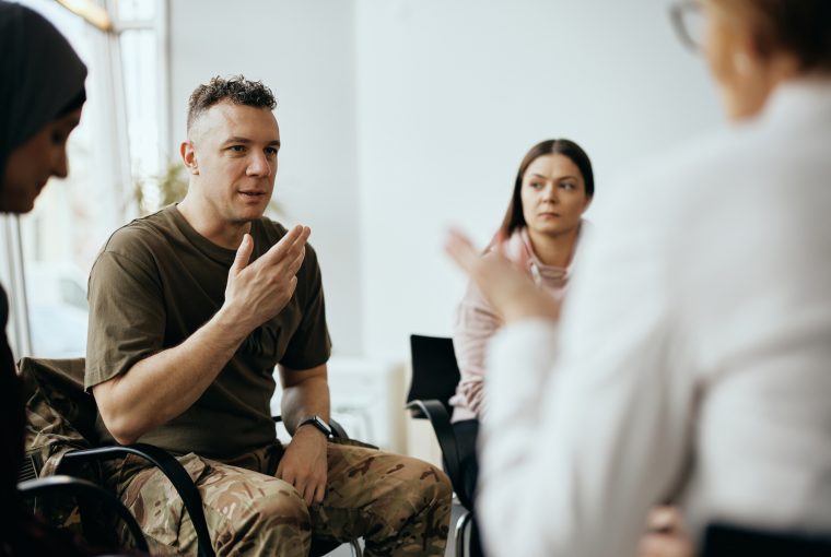 a man talking to a group in a therapy session.