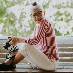 a senior in a striped shirt holding a camera