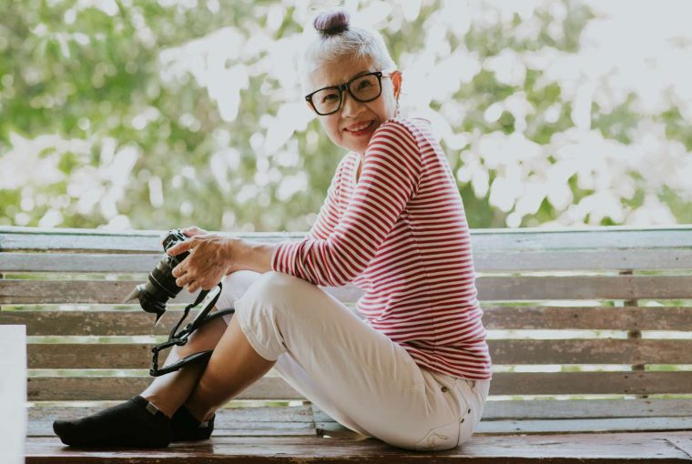 a senior in a striped shirt holding a camera
