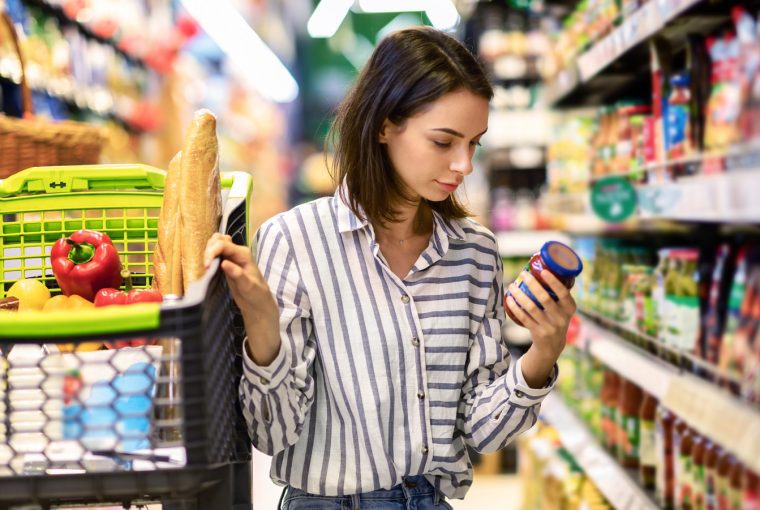 a woman looking at a can of food on the shelf