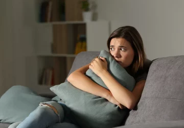 a woman holding a pillow in fear
