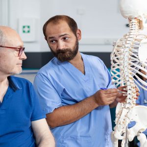 a chiropractor showing a patient a skeleton