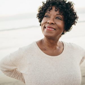 a senior woman standing on the beach smiling