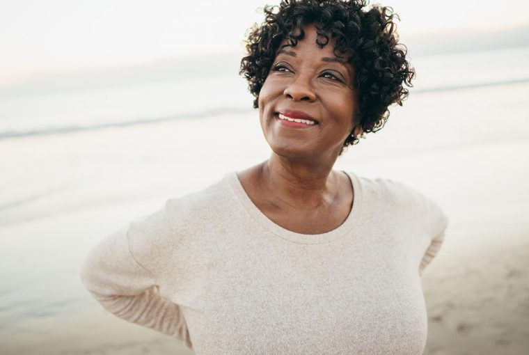 a senior woman standing on the beach smiling