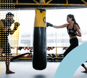 a trainer and a client hitting a heavy bag