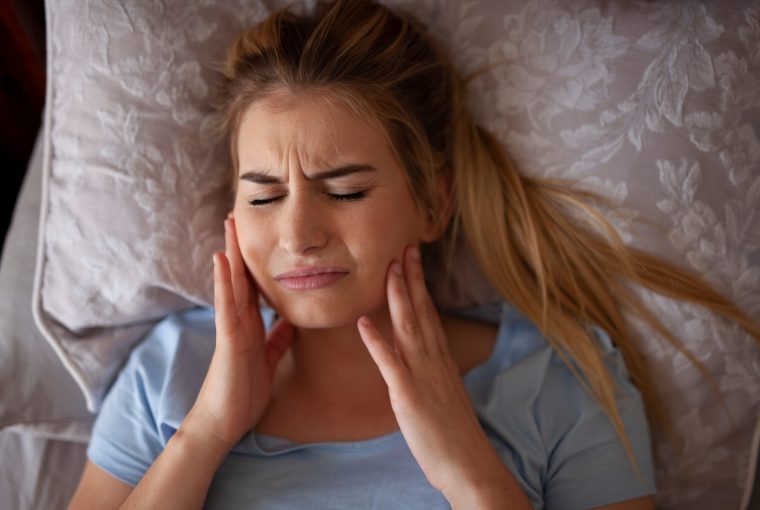 a woman holding her jaw in pain