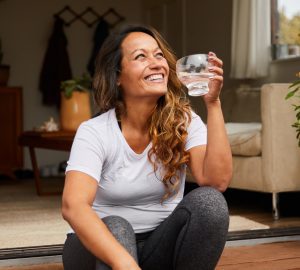 a woman sitting outside drinking a glass of water