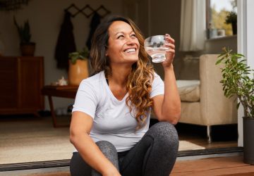 a woman sitting outside drinking a glass of water