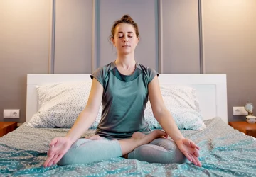 a woman meditating in bed