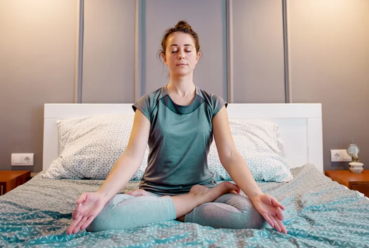 a woman meditating in bed