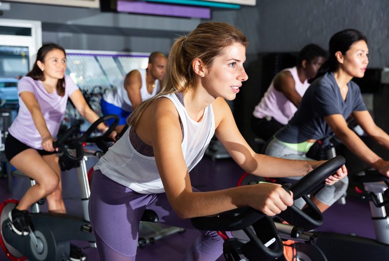 Portrait of sporty young adult woman doing cardio workout cycling bike