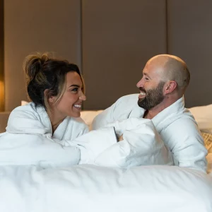 a couple wearing robes lying in bed