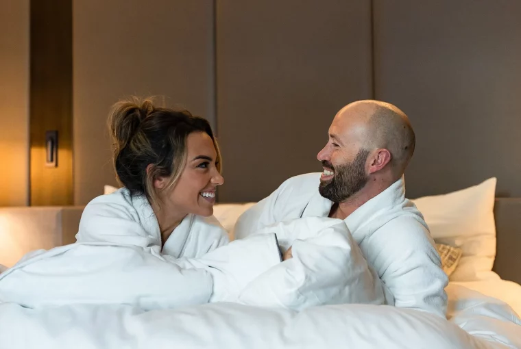 a couple wearing robes lying in bed