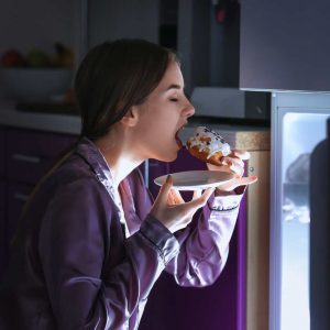 a woman eating a donught in the dark