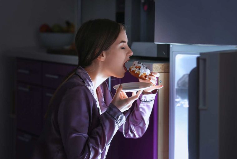 a woman eating a donught in the dark