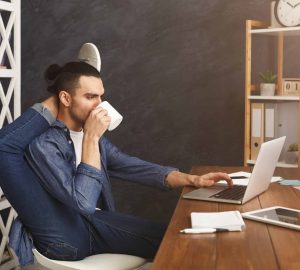 a man drinking coffee in front of the computer