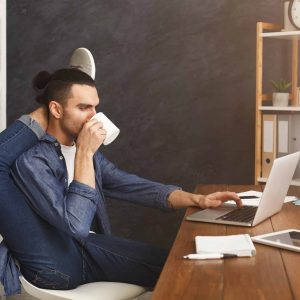 a man drinking coffee in front of the computer