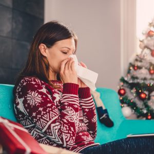 a woman blowing her nose in a Christmas sweater