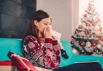 a woman blowing her nose in a Christmas sweater