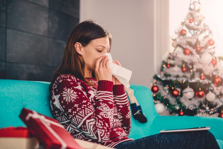 a woman blowing her nose in a Christmas sweater