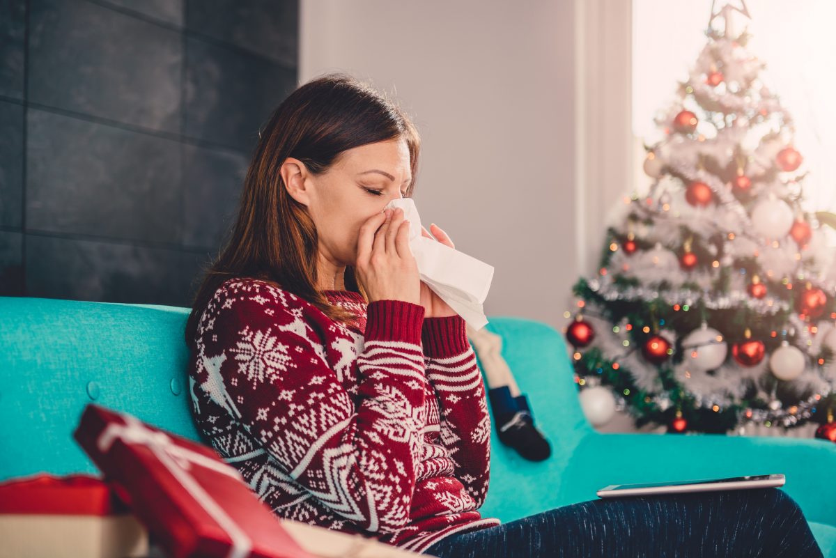 a woman blowing her nose in a Christmas sweater