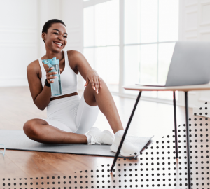 a woman drinking water while looking at her computer screen