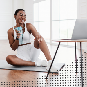 a woman drinking water while looking at her computer screen