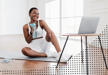 a woman drinking water while looking at her computer screen