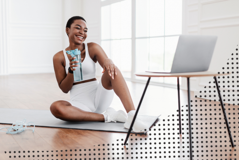 a woman drinking water while looking at her computer screen