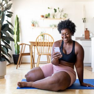 a woman sitting on the floor smiling at her phone