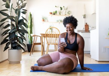a woman sitting on the floor smiling at her phone