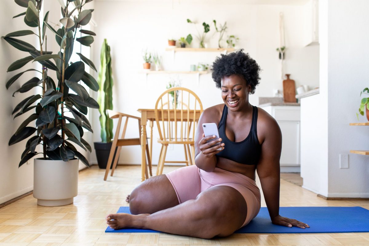 a woman sitting on the floor smiling at her phone