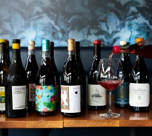 a person pouring a glass of wine and a selection of organic wines.