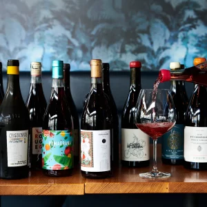 a person pouring a glass of wine and a selection of organic wines.