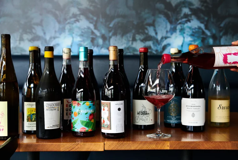 a person pouring a glass of wine and a selection of organic wines.