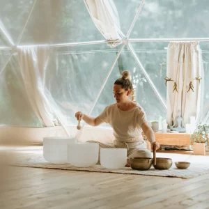 a woman on the floow performing a sound bath